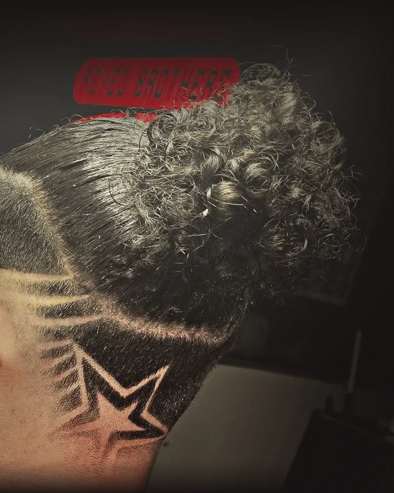 Back of a client's head: a high fade with a star shaved in and curls on top